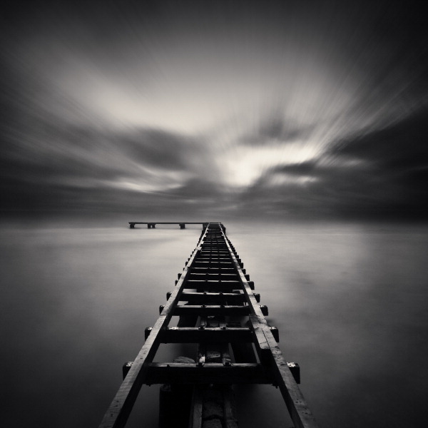 Old Pier At Dusk, photography by Denis Olivier. S&oslash;nderborg, Denmark, October 21, 2008 - #1204
http://www.denisolivier.com/p_sets.php?pid=1204

You can't see it very well on the clich&eacute;, but it was raining hard on me from the clouds over and behind me. The fog, mixed with the rain and the light was making a fantastic exposure, but I have the tripod and my feet between the rails and an umbrella in the hand, trying to protect the equipment. And to complete the scene, the fast wind from the sea made it all unstable. You just need to stop thinking during several minutes .... In Nature, Scenery, Waterspace
