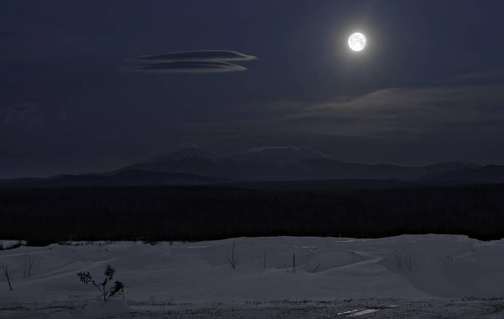 Wolf Moon - January 2010, photography by Craig Robinson. The Wolf Moon is a full moon that occurs in January. Its name comes from hungry wolf packs that would howl outside the villages of Native Americans. 
It was extremely cold and windy the night this photo was taken. The wind chill factor ranged between -30&deg;F and -60&deg;F. Note the two, standing lenticular clouds over Mt. Katahdin. They were visible and stable from 1AM to 6:45 AM.   This is a long time for that type of cloud to remain intact. 
I spent the entire night roaming the woods and fields. The experience was awesome! 
. D3. In Nature, Scenery, Countryside